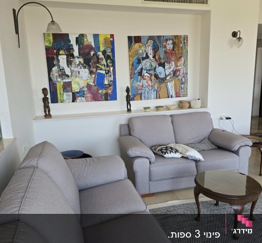 סלון עם ספות, שולחן קטן ותמונות על הקיר